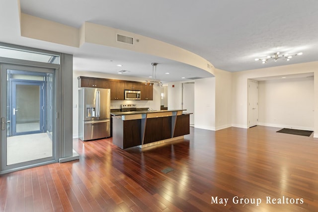 kitchen featuring dark hardwood / wood-style flooring, hanging light fixtures, a center island, and appliances with stainless steel finishes