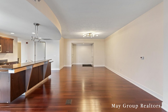 kitchen featuring hanging light fixtures and dark wood-type flooring