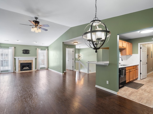 kitchen featuring vaulted ceiling, sink, dishwasher, decorative light fixtures, and light hardwood / wood-style floors