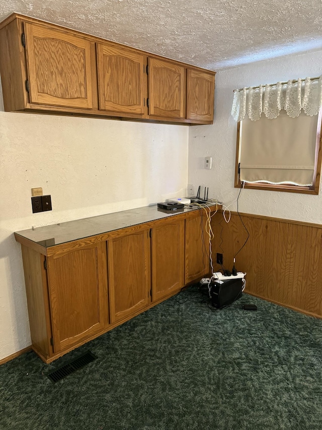 kitchen featuring dark carpet and a textured ceiling