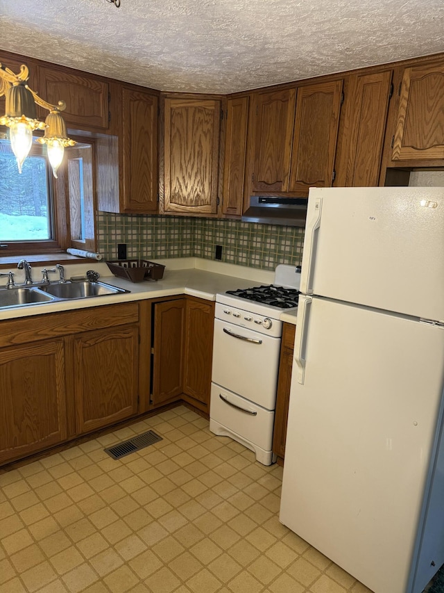 kitchen featuring pendant lighting, tasteful backsplash, sink, white appliances, and a textured ceiling