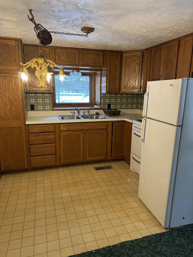 kitchen featuring sink, decorative light fixtures, white fridge, stove, and backsplash