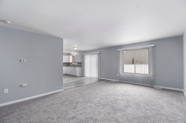 unfurnished living room with light carpet and baseboards