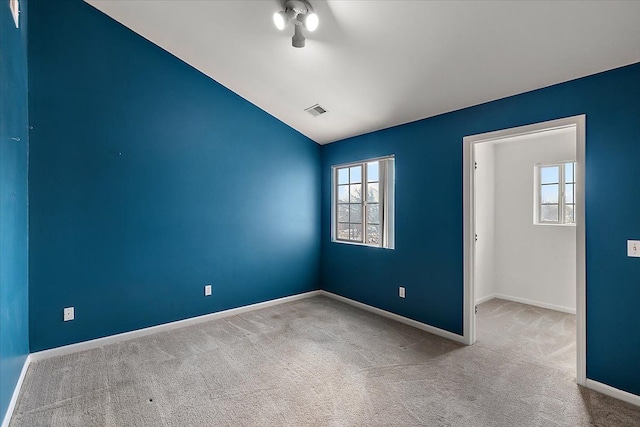 carpeted empty room with vaulted ceiling