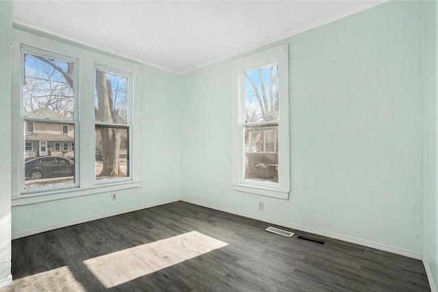 empty room with dark wood-type flooring, ornamental molding, and a healthy amount of sunlight