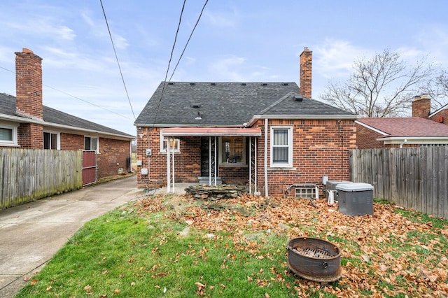 rear view of property featuring a lawn, covered porch, and an outdoor fire pit