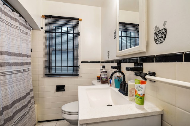 bathroom featuring vanity, toilet, and tile walls