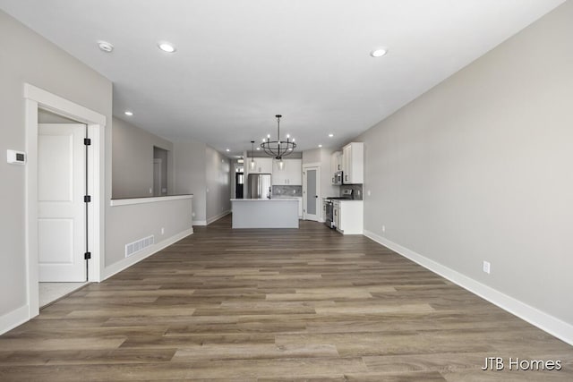 unfurnished living room featuring hardwood / wood-style flooring and an inviting chandelier