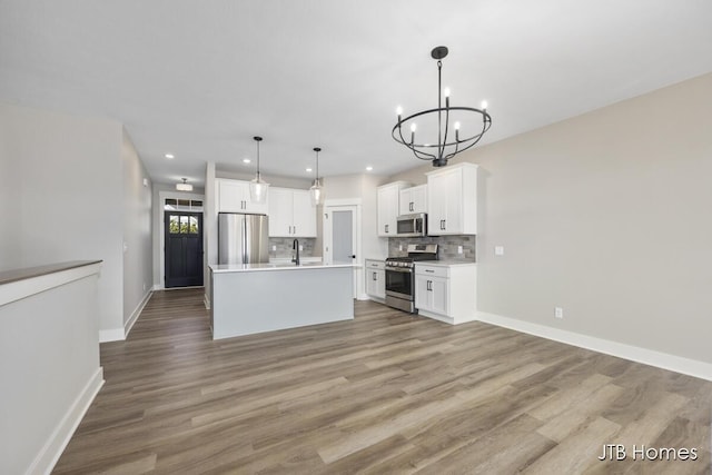 kitchen with a center island, hanging light fixtures, appliances with stainless steel finishes, decorative backsplash, and white cabinets