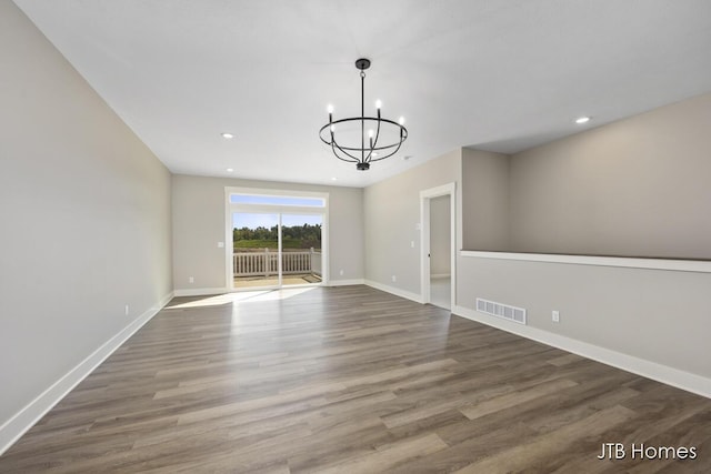 unfurnished room with a notable chandelier and dark hardwood / wood-style floors