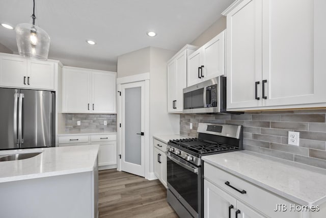 kitchen with white cabinetry, appliances with stainless steel finishes, and decorative light fixtures