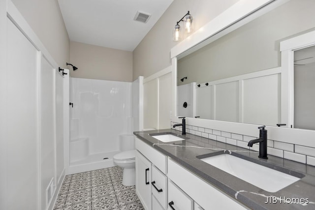 bathroom featuring vanity, decorative backsplash, tile patterned floors, toilet, and walk in shower