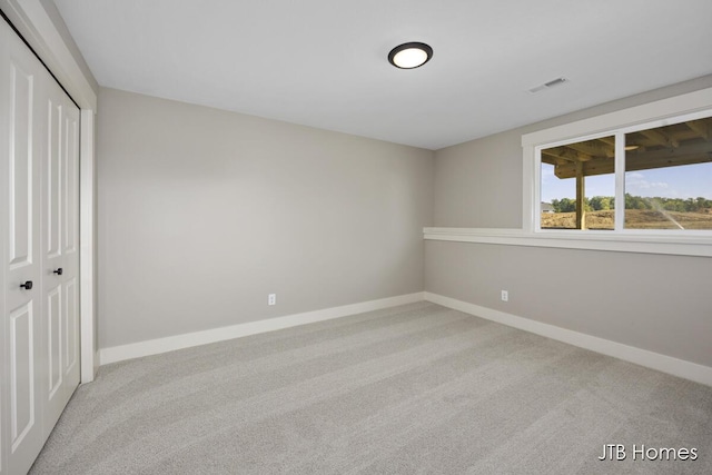 unfurnished bedroom with light colored carpet and a closet