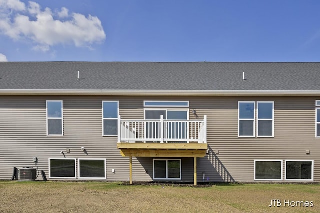 back of property with central AC and a lawn