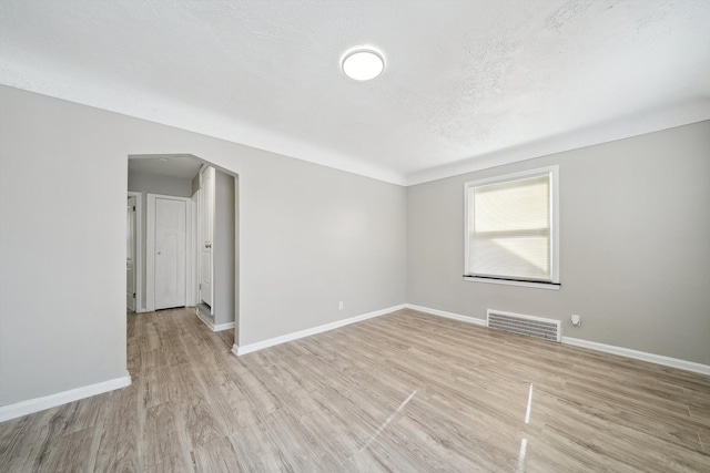 spare room featuring light hardwood / wood-style floors and a textured ceiling