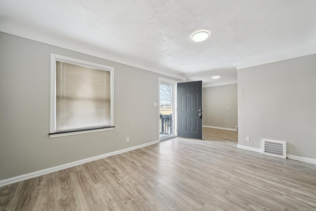 spare room with light hardwood / wood-style flooring and a textured ceiling