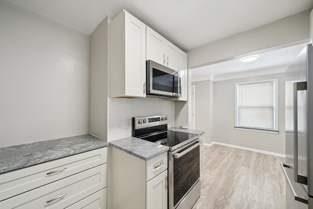 kitchen featuring white cabinetry, light hardwood / wood-style flooring, stainless steel appliances, light stone countertops, and backsplash