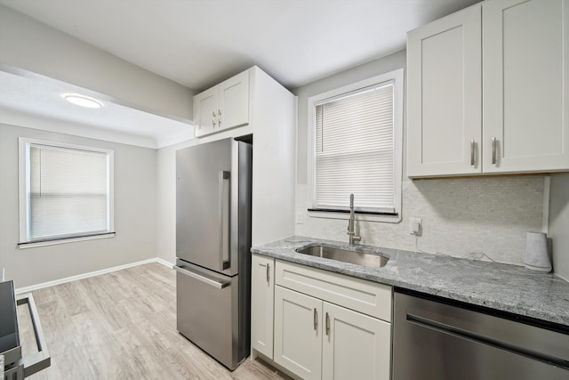 kitchen featuring sink, white cabinets, light stone counters, light hardwood / wood-style floors, and stainless steel appliances