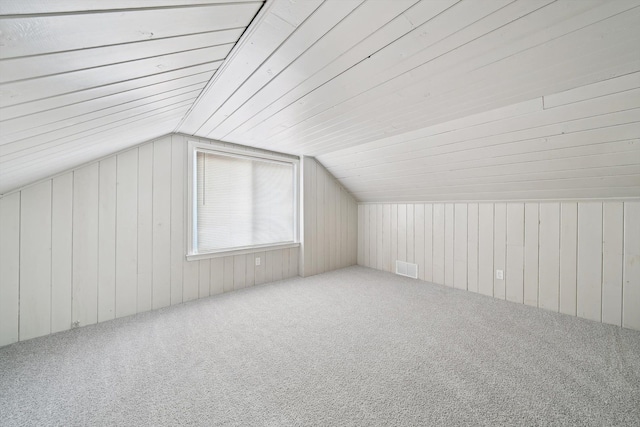 additional living space with lofted ceiling, carpet floors, and wood walls