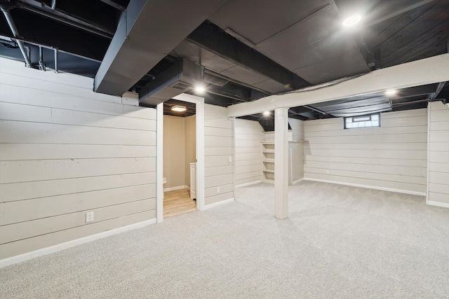 basement with light colored carpet and wood walls