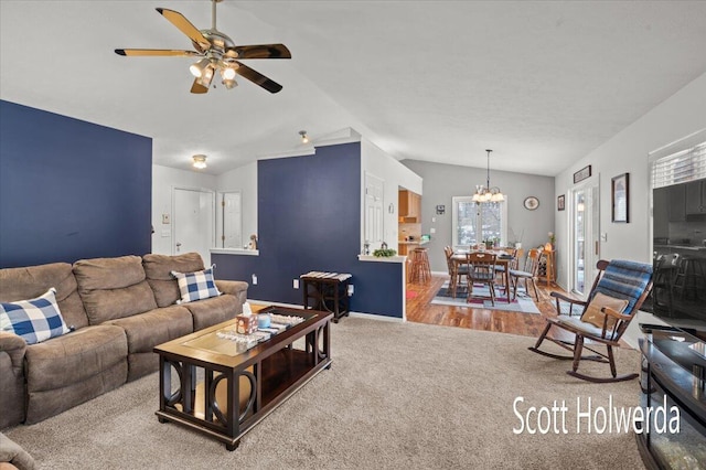 living room with lofted ceiling, carpet flooring, and ceiling fan with notable chandelier