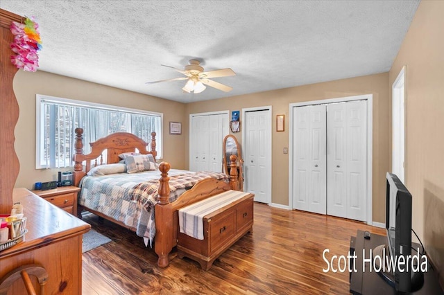 bedroom featuring two closets, a textured ceiling, and dark hardwood / wood-style flooring