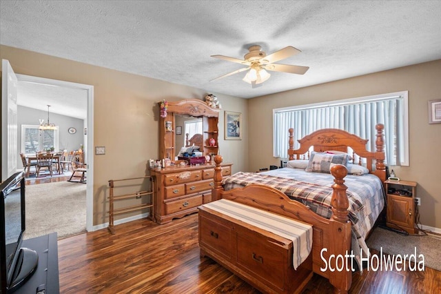 bedroom with dark hardwood / wood-style flooring, ceiling fan with notable chandelier, and a textured ceiling