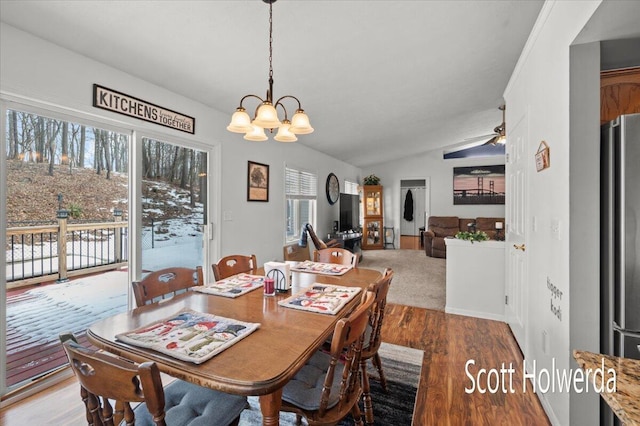 dining room featuring hardwood / wood-style flooring, vaulted ceiling, ceiling fan with notable chandelier, and a wealth of natural light