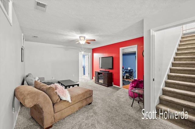 carpeted living room with ceiling fan and a textured ceiling