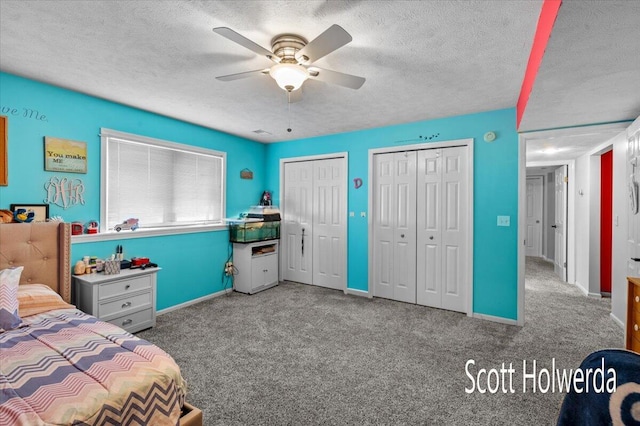 carpeted bedroom with ceiling fan, two closets, and a textured ceiling