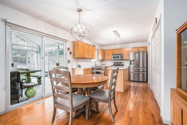 dining room with an inviting chandelier, sink, and light hardwood / wood-style floors