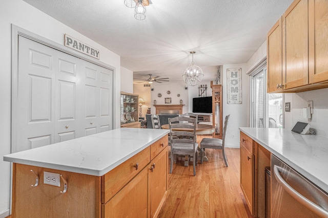 kitchen with pendant lighting, a center island, light hardwood / wood-style floors, ceiling fan with notable chandelier, and stainless steel dishwasher