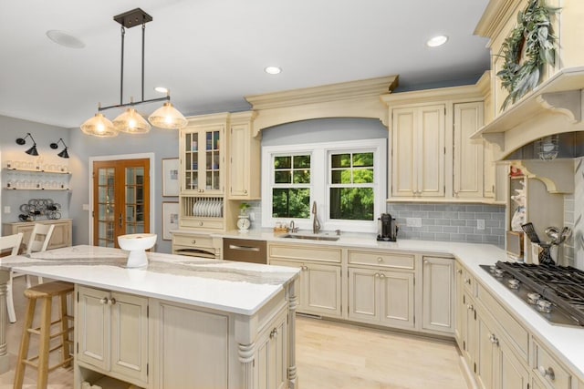 kitchen with sink, cream cabinets, stainless steel gas cooktop, and a kitchen bar