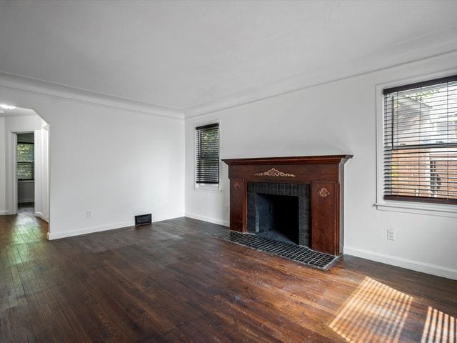 unfurnished living room featuring a tiled fireplace and dark hardwood / wood-style flooring