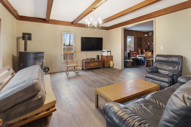 living room featuring beamed ceiling, a chandelier, hardwood / wood-style floors, and a wood stove