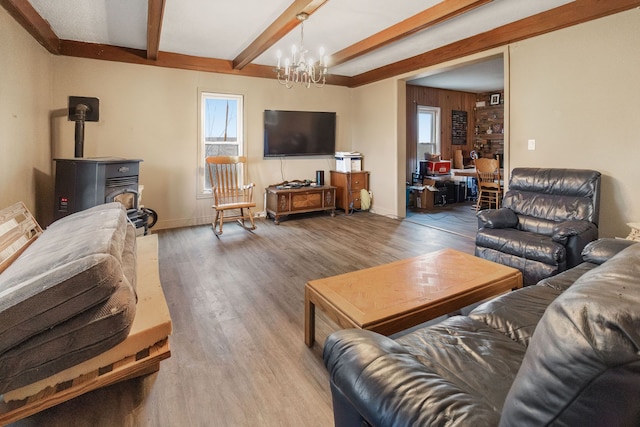 living room with hardwood / wood-style flooring, a wood stove, a notable chandelier, and beam ceiling