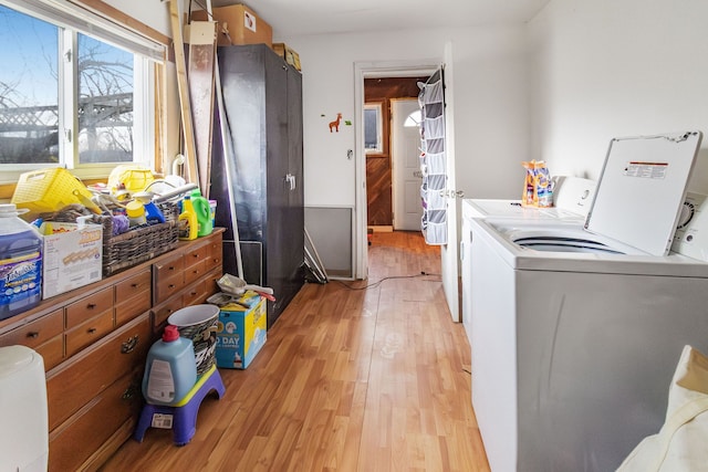 clothes washing area with separate washer and dryer and light wood-type flooring