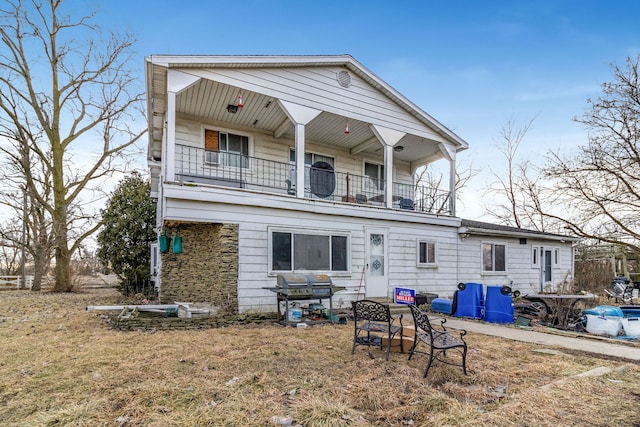 rear view of house with a balcony and a lawn