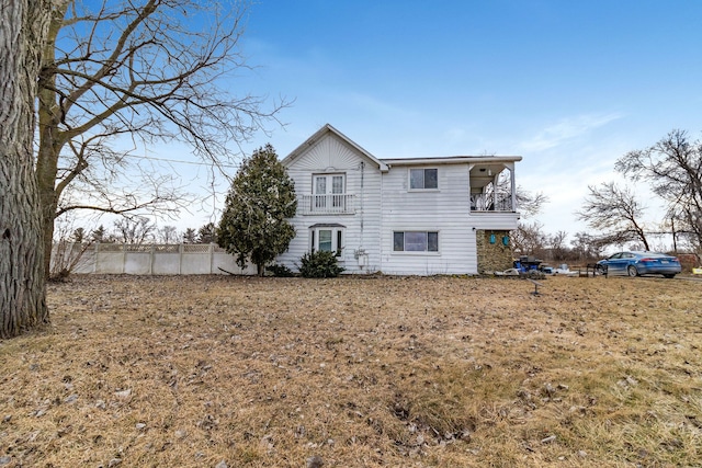 rear view of property with a balcony and a yard