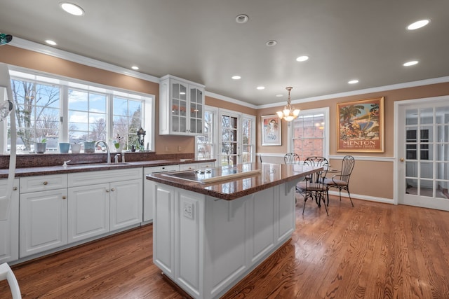 kitchen with a kitchen island, sink, pendant lighting, and white cabinets