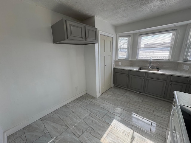 kitchen with sink, gray cabinets, a textured ceiling, and range