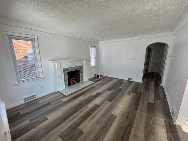 unfurnished living room with dark wood-type flooring, a premium fireplace, a textured ceiling, and crown molding