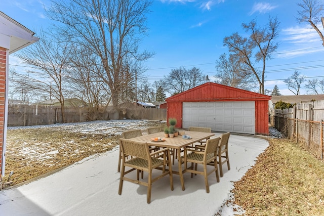 snow covered patio featuring an outbuilding and a garage