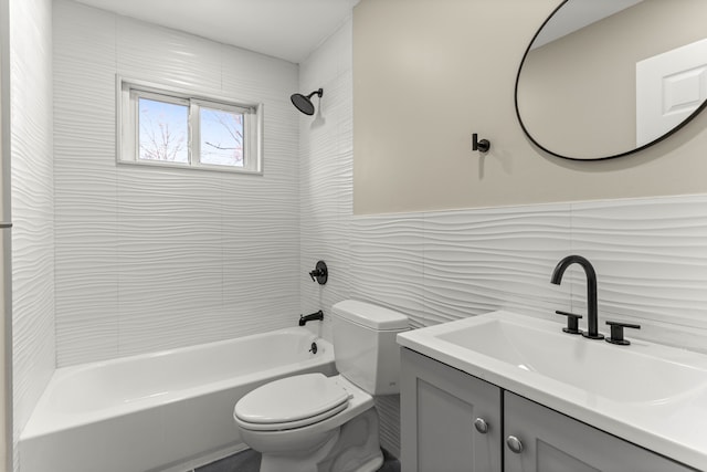 full bathroom featuring tiled shower / bath, vanity, toilet, and tile walls