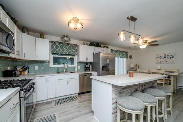 kitchen featuring sink, white cabinetry, hanging light fixtures, a kitchen island, and stainless steel appliances