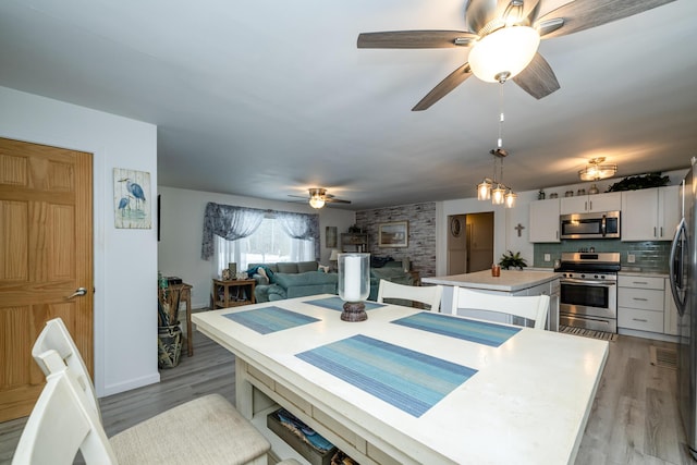 dining space with ceiling fan and light wood-type flooring