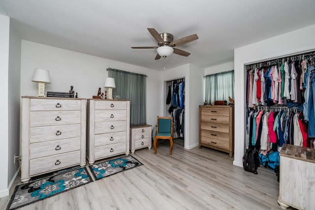 interior space featuring multiple closets, ceiling fan, and light wood-type flooring