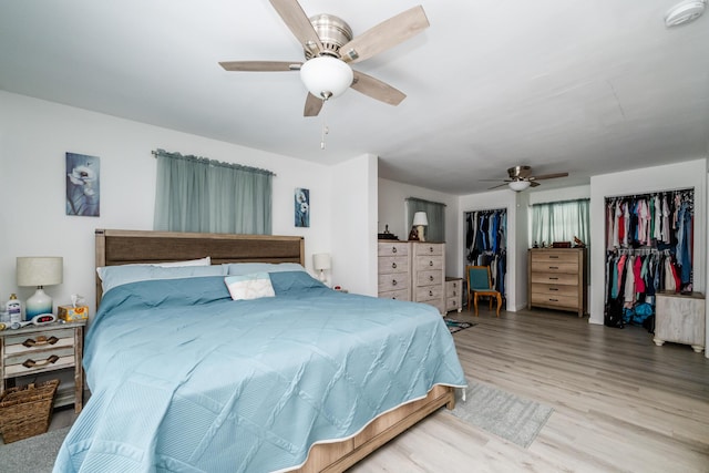 bedroom featuring ceiling fan, light hardwood / wood-style floors, and two closets