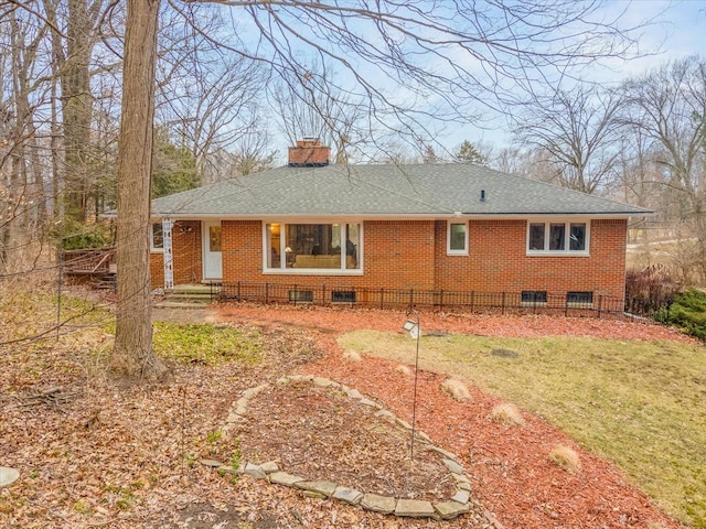 rear view of property featuring brick siding, a yard, a chimney, and roof with shingles