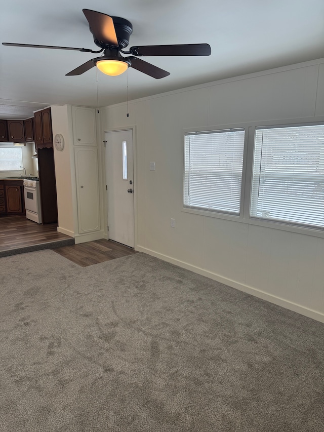 unfurnished living room featuring ceiling fan and dark carpet